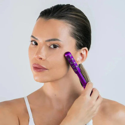 Woman using a purple hair straightener on her hair against a plain background